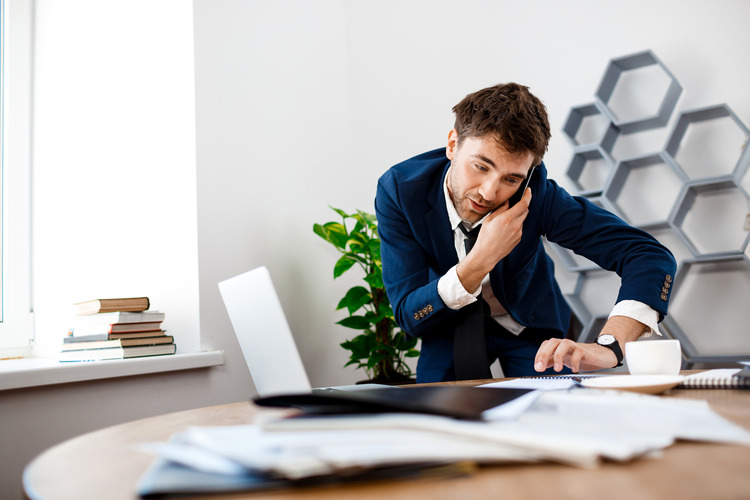 absentminded young businessman speaking phone office